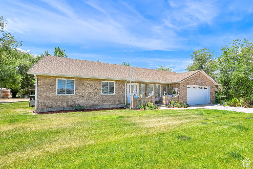 Single story home with concrete driveway, brick siding, a front lawn, an attached garage, and a shingled roof