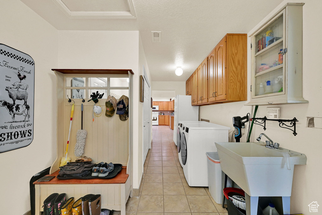 Washroom with cabinet space, light tile patterned floors, and washer and clothes dryer
