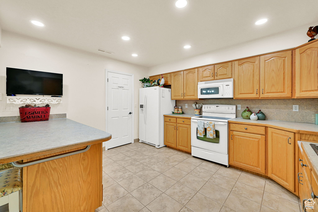 Kitchen with white appliances, a peninsula, tasteful backsplash, recessed lighting, and light countertops