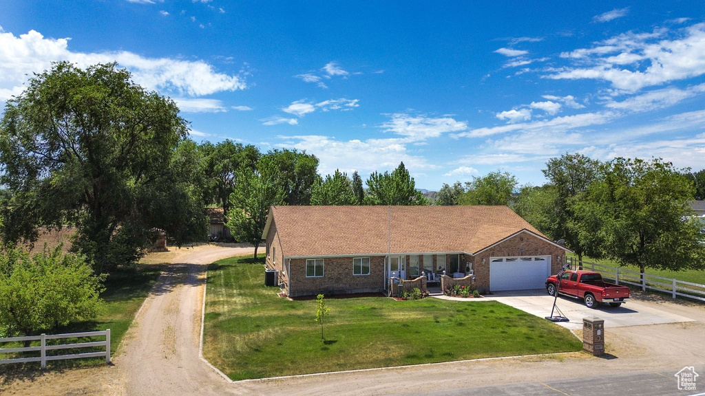 View of front of house featuring concrete driveway, a garage, brick siding, and view of scattered trees