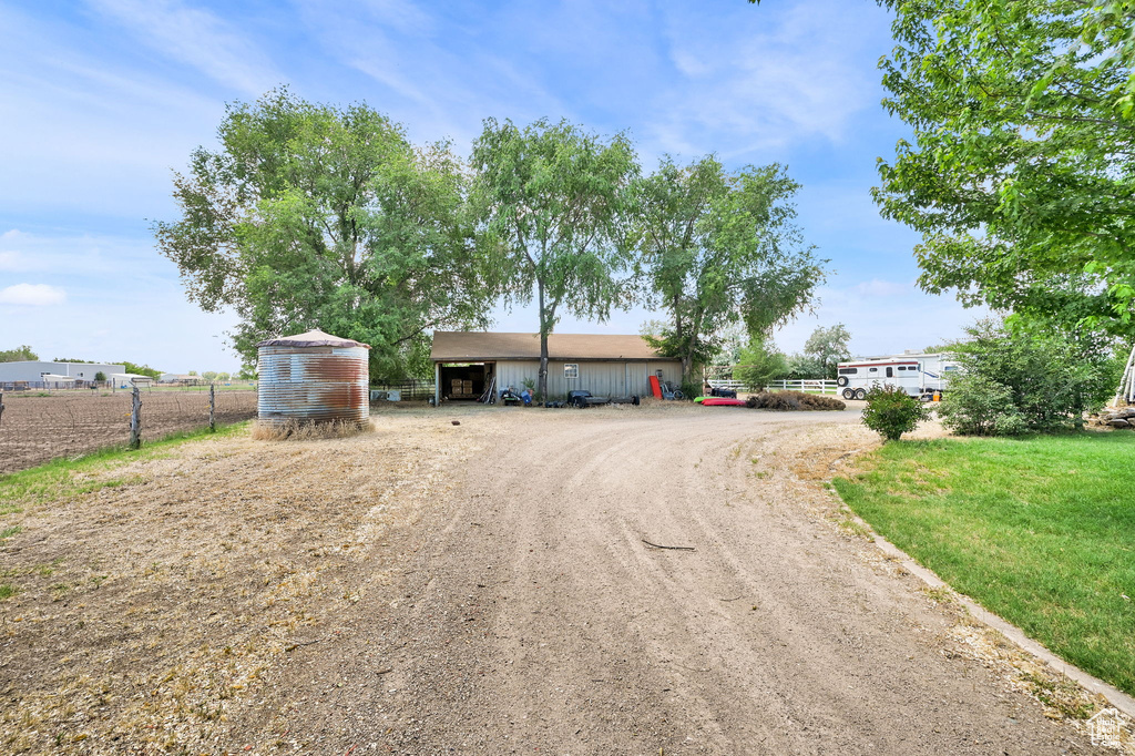 View of front of house featuring dirt driveway and an outdoor structure