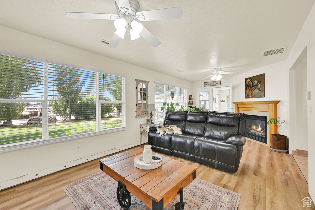Living area featuring a ceiling fan, light wood finished floors, and a fireplace