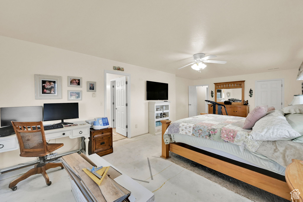 Bedroom with a desk, concrete floors, and a ceiling fan