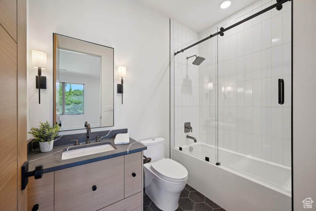 Full bath featuring toilet, vanity, bath / shower combo with glass door, and tile patterned flooring