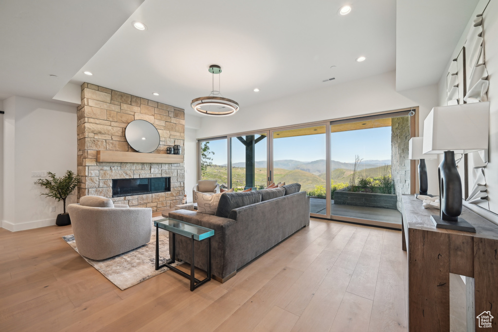 Living area with a fireplace, light wood-style flooring, recessed lighting, and a mountain view