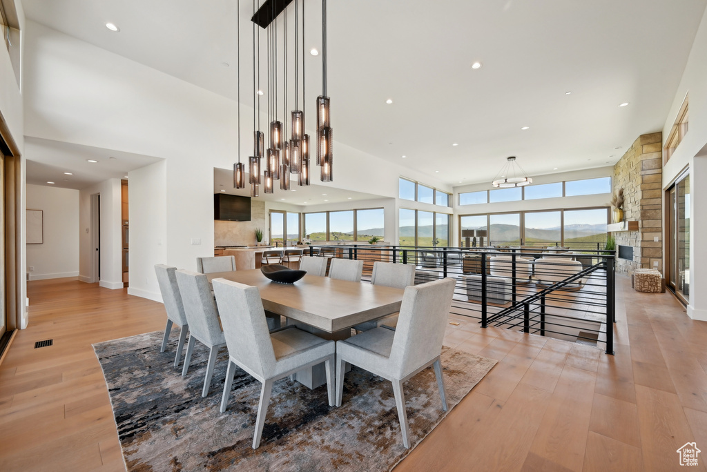 Dining space with a chandelier, light wood-style flooring, a towering ceiling, recessed lighting, and baseboards