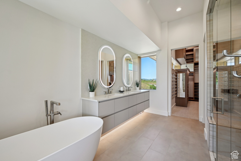 Bathroom with double vanity, a freestanding tub, a shower stall, baseboards, and recessed lighting
