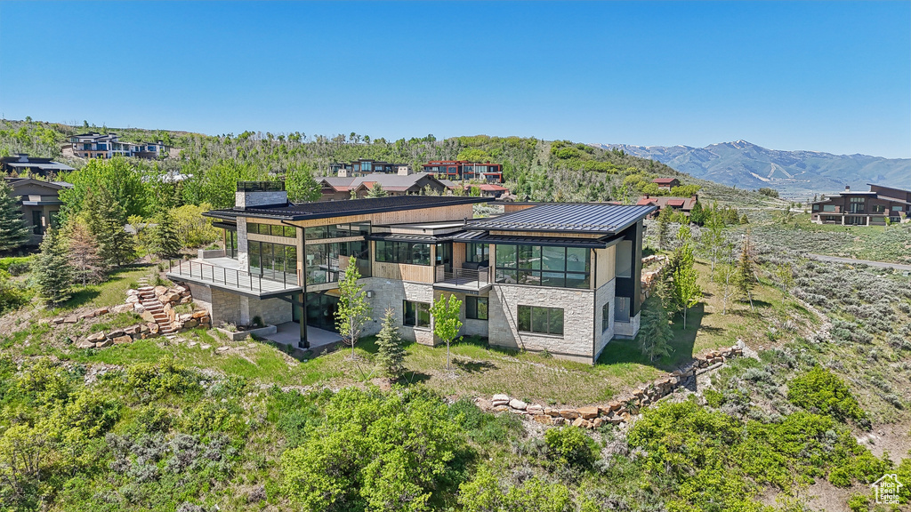View of front of property with stairs, a standing seam roof, a deck with mountain view, and stone siding