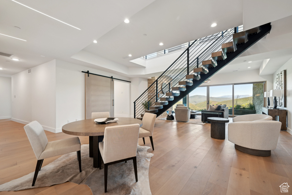 Dining space with a barn door, stairway, light wood-type flooring, recessed lighting, and baseboards