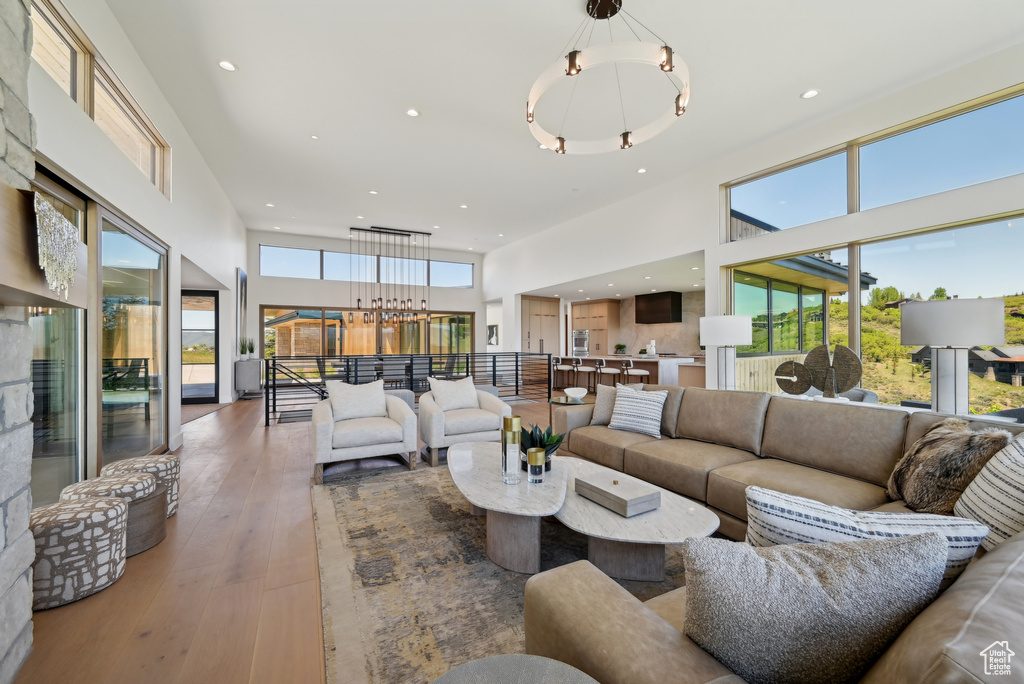 Living room with a chandelier, a towering ceiling, wood-type flooring, and recessed lighting