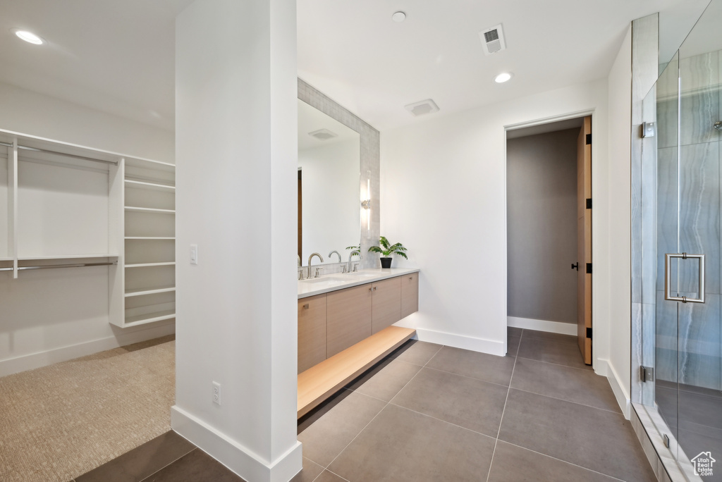 Bathroom featuring vanity, a stall shower, a spacious closet, tile patterned flooring, and baseboards
