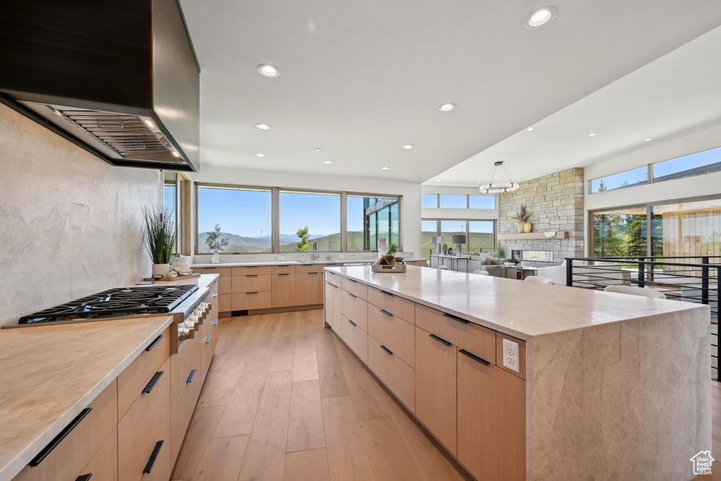 Kitchen featuring light brown cabinets, modern cabinets, wall chimney range hood, recessed lighting, and light wood-type flooring