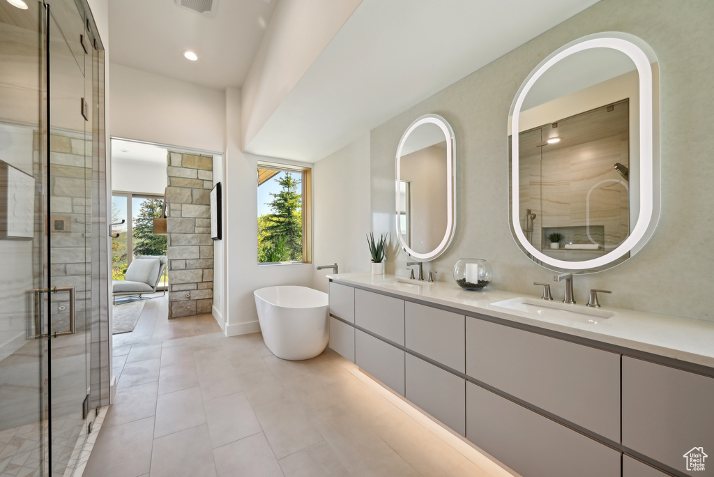 Bathroom featuring double vanity, a freestanding bath, a stall shower, tile patterned floors, and recessed lighting