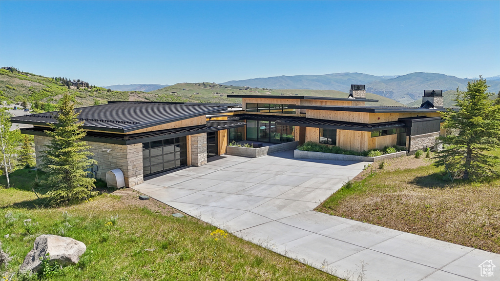 View of front of house featuring a standing seam roof, stone siding, a mountain view, and a chimney