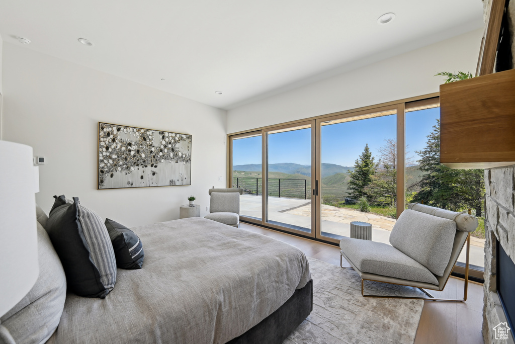 Bedroom featuring a mountain view, access to exterior, wood finished floors, and a fireplace