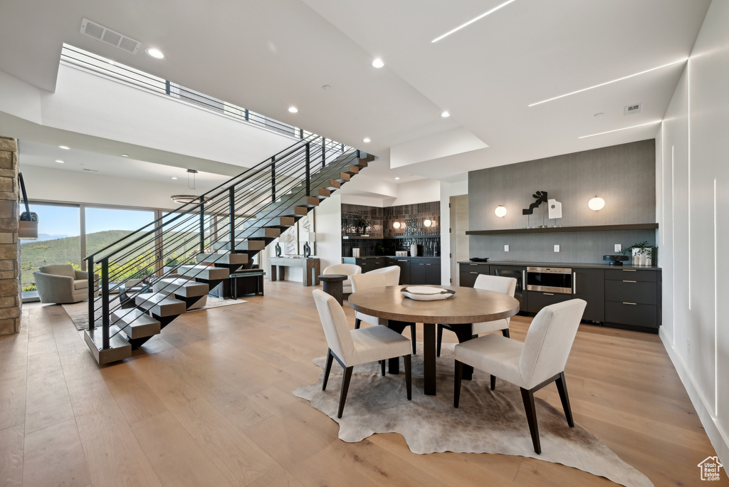 Dining space featuring stairs, light wood-style floors, bar, and recessed lighting