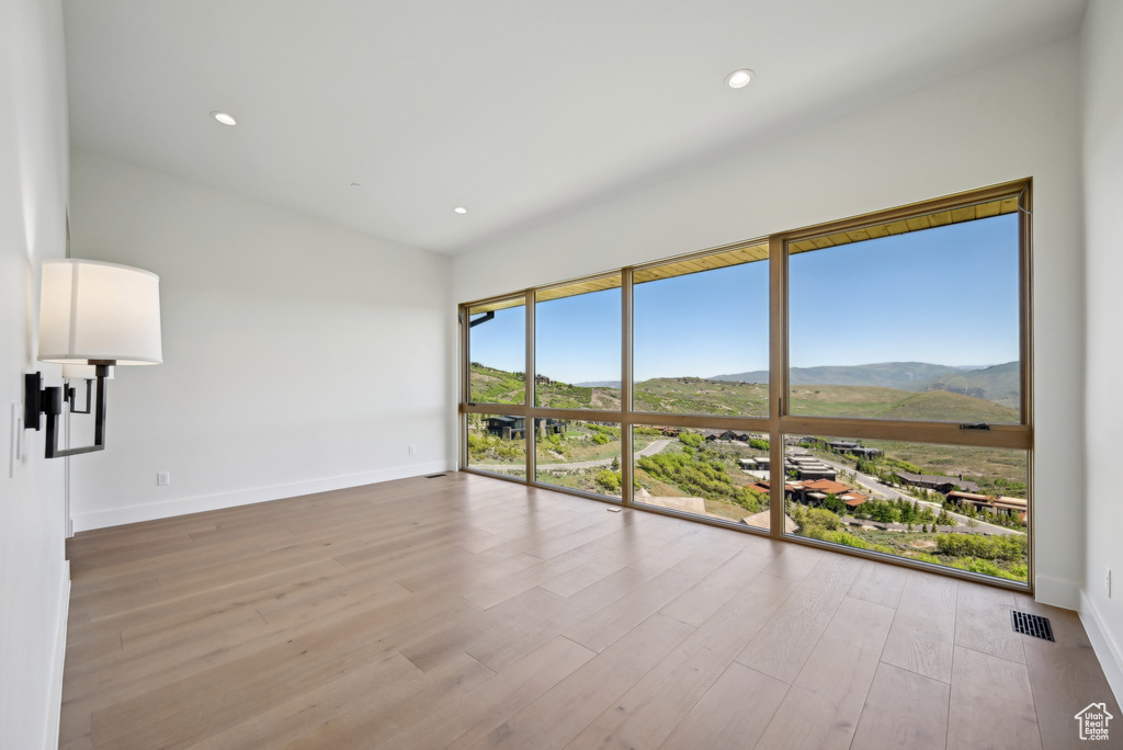 Unfurnished room featuring a mountain view, baseboards, wood finished floors, and recessed lighting