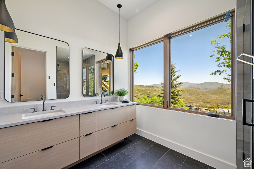 Bathroom with a mountain view, double vanity, baseboards, tile patterned floors, and a shower with shower door