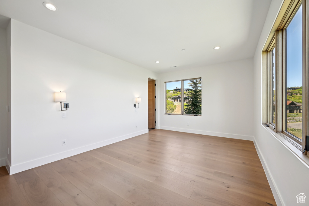 Empty room featuring baseboards, light wood-style floors, and recessed lighting