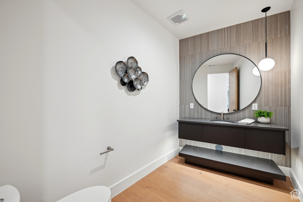 Bathroom with toilet, wood finished floors, vanity, and baseboards