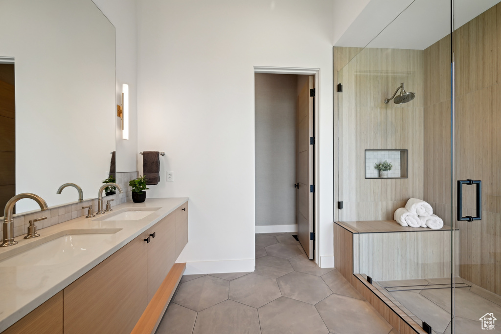 Full bath with a stall shower, double vanity, tile patterned flooring, and baseboards
