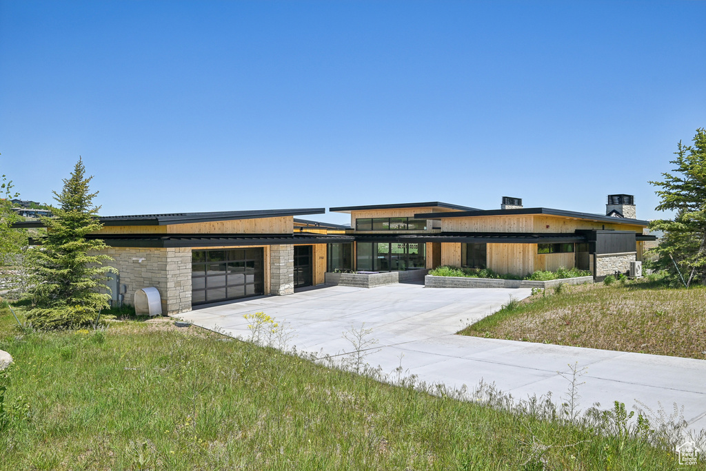 Contemporary house featuring concrete driveway, stone siding, and an attached garage