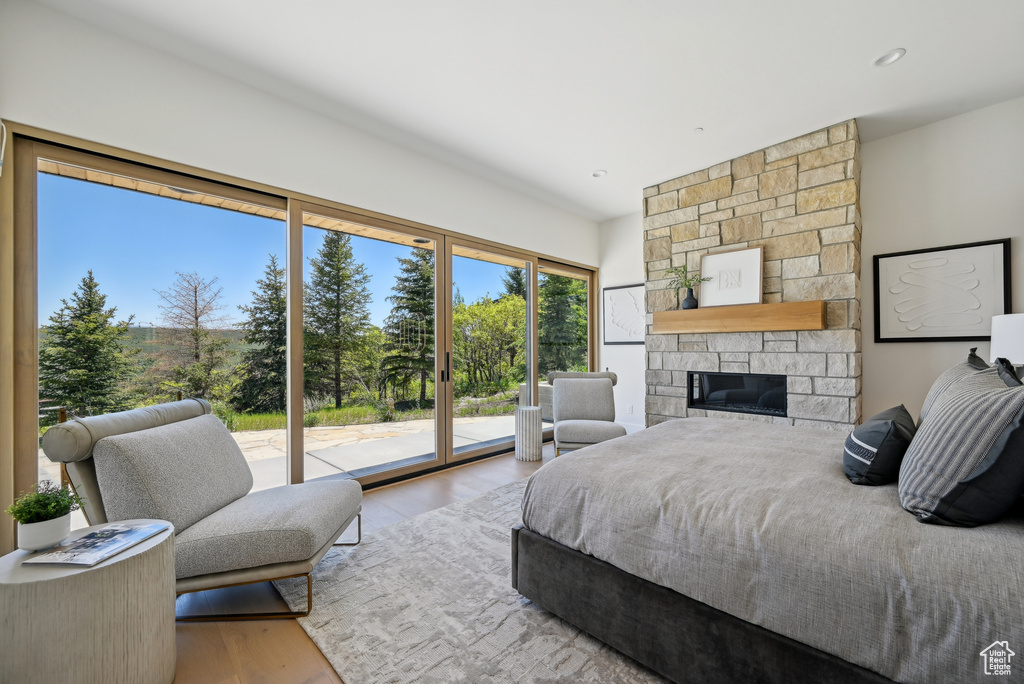 Bedroom with access to outside, wood finished floors, and a fireplace