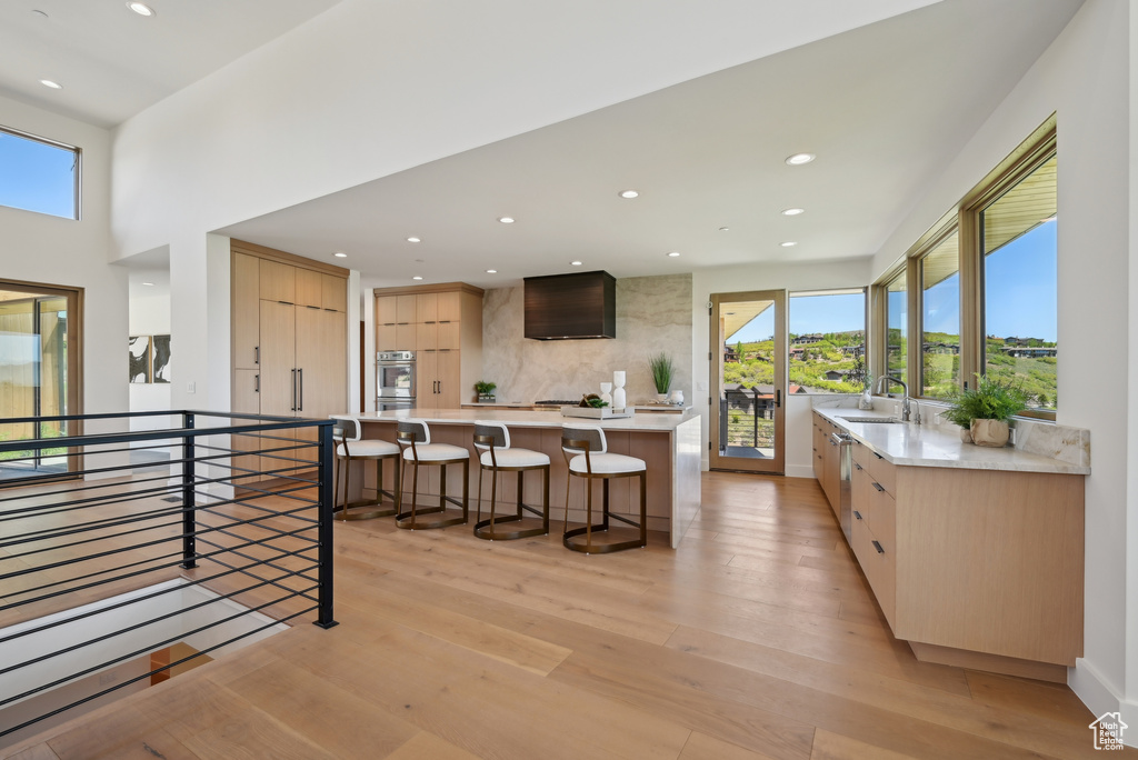 Kitchen featuring light brown cabinetry, a kitchen breakfast bar, light countertops, decorative backsplash, and modern cabinets