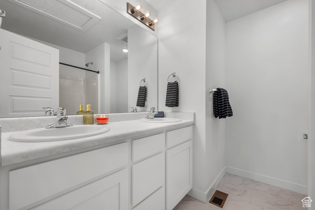 Full bathroom with marble look tiles, double vanity, and a shower
