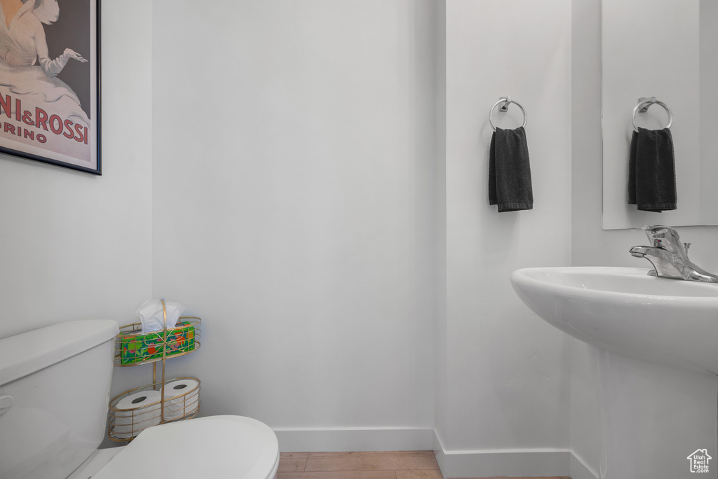 Half bath with toilet and wood finished floors