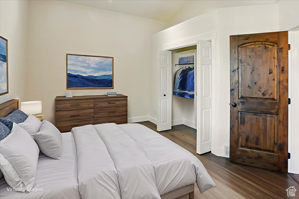 Bedroom featuring dark wood-style floors and vaulted ceiling