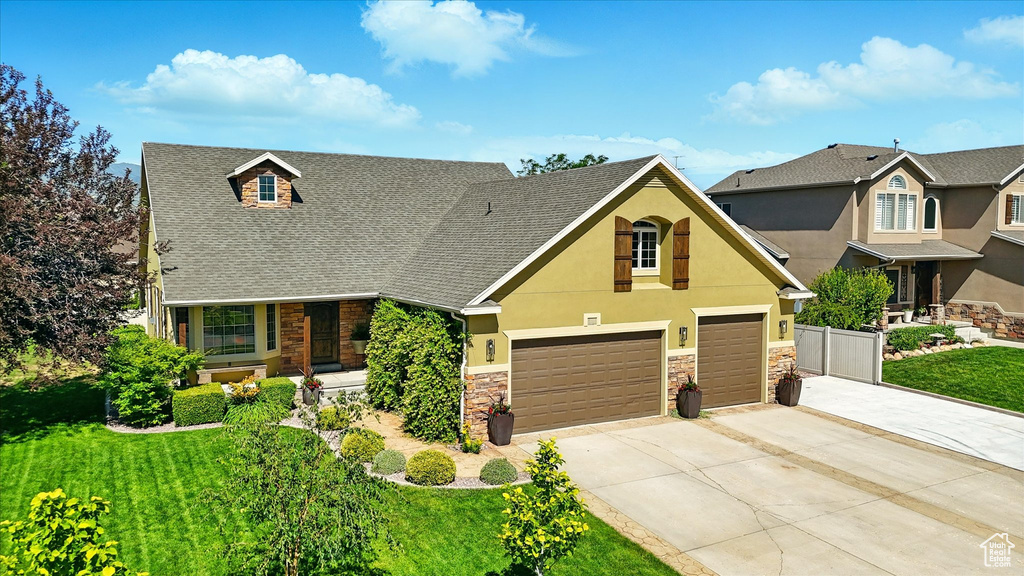 View of front of home with stone siding, concrete driveway, a front yard, and stucco siding
