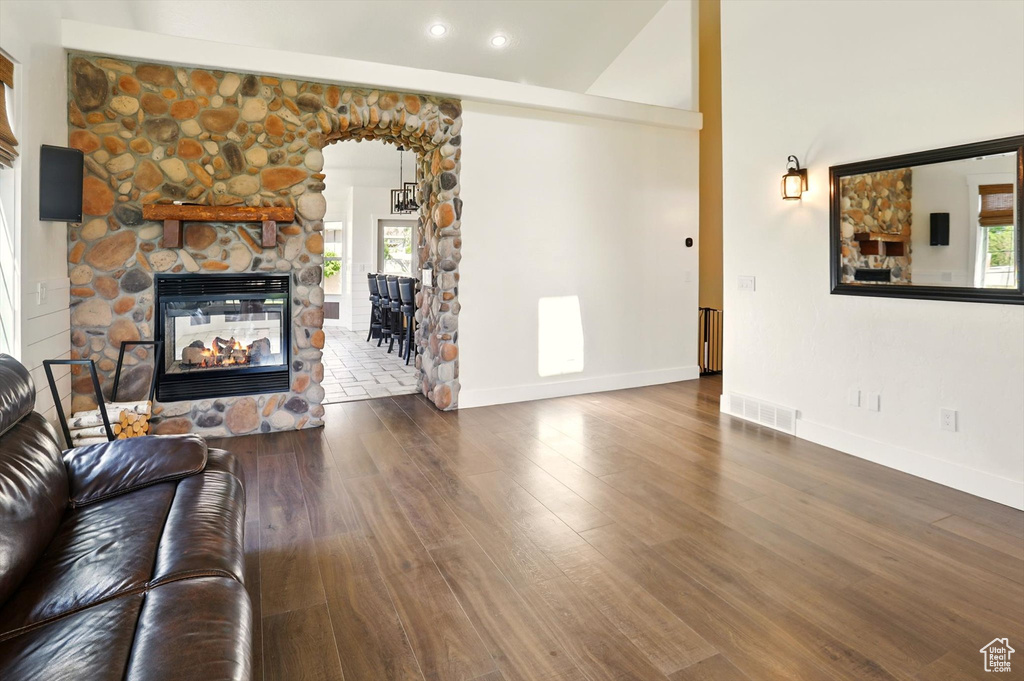 Living room with a fireplace, wood finished floors, recessed lighting, and arched walkways