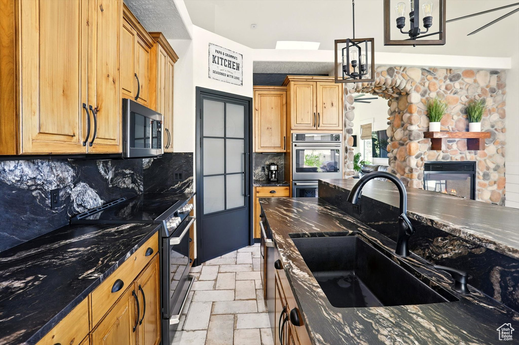 Kitchen featuring black electric range oven, decorative backsplash, a chandelier, decorative light fixtures, and dark stone counters