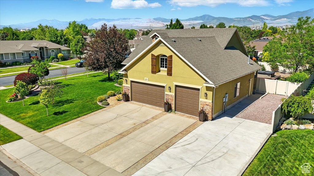 Traditional-style home with stucco siding, concrete driveway, an attached garage, stone siding, and a mountain view