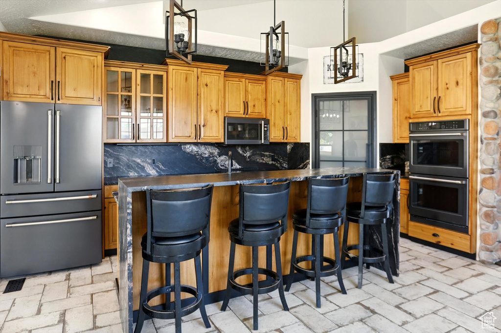 Kitchen featuring appliances with stainless steel finishes, dark countertops, backsplash, and a center island