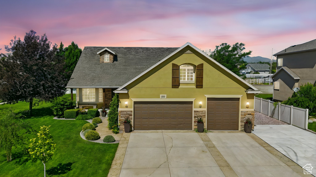 View of front of home with stone siding, driveway, stucco siding, and an attached garage