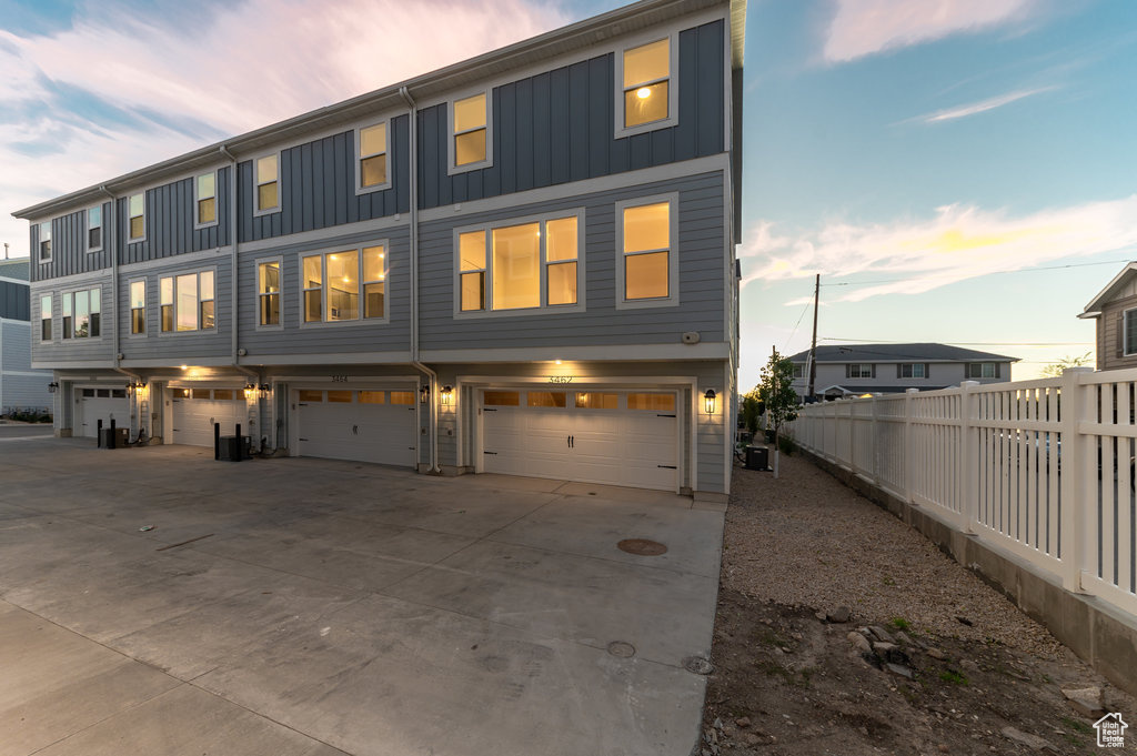 View of front of property featuring board and batten siding, an attached garage, and driveway