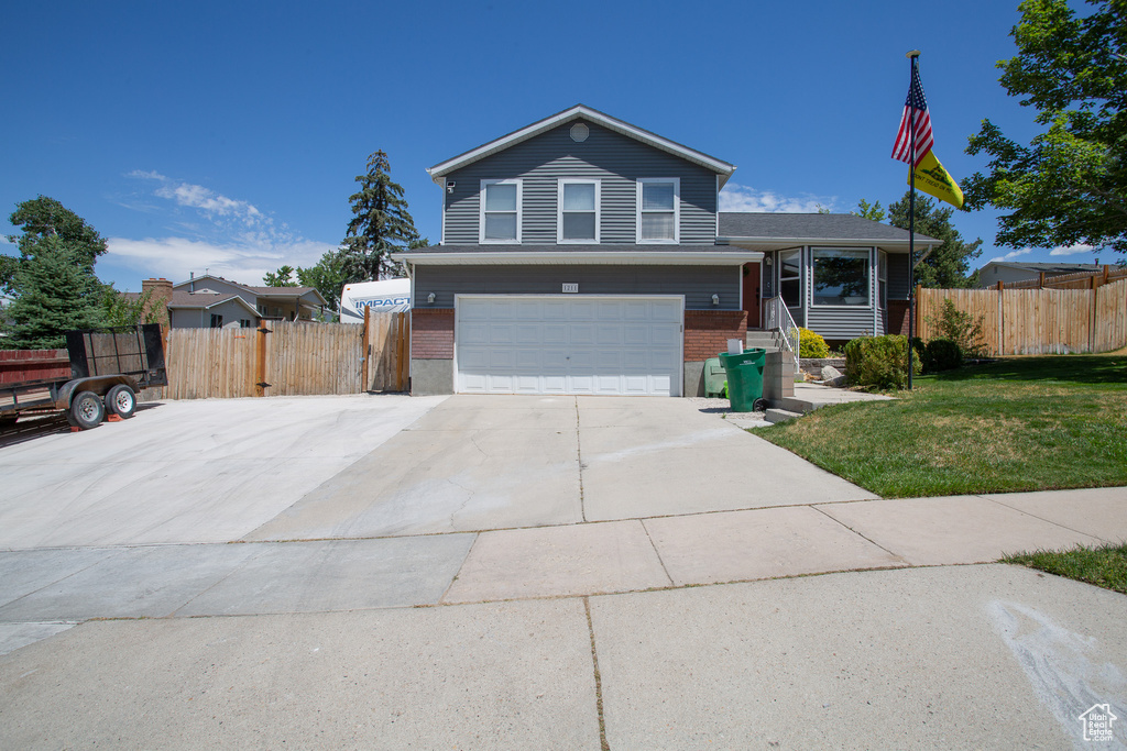 Tri-level home featuring brick siding, an attached garage, and driveway