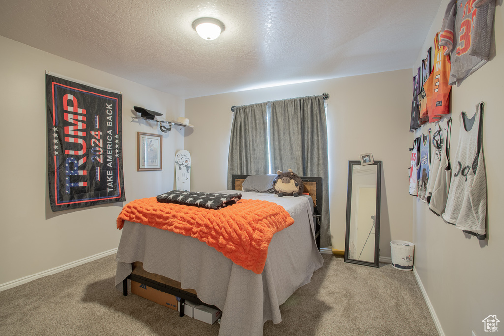 Carpeted bedroom with baseboards and a textured ceiling