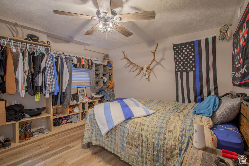 Bedroom with a textured ceiling, wood finished floors, a ceiling fan, and a closet