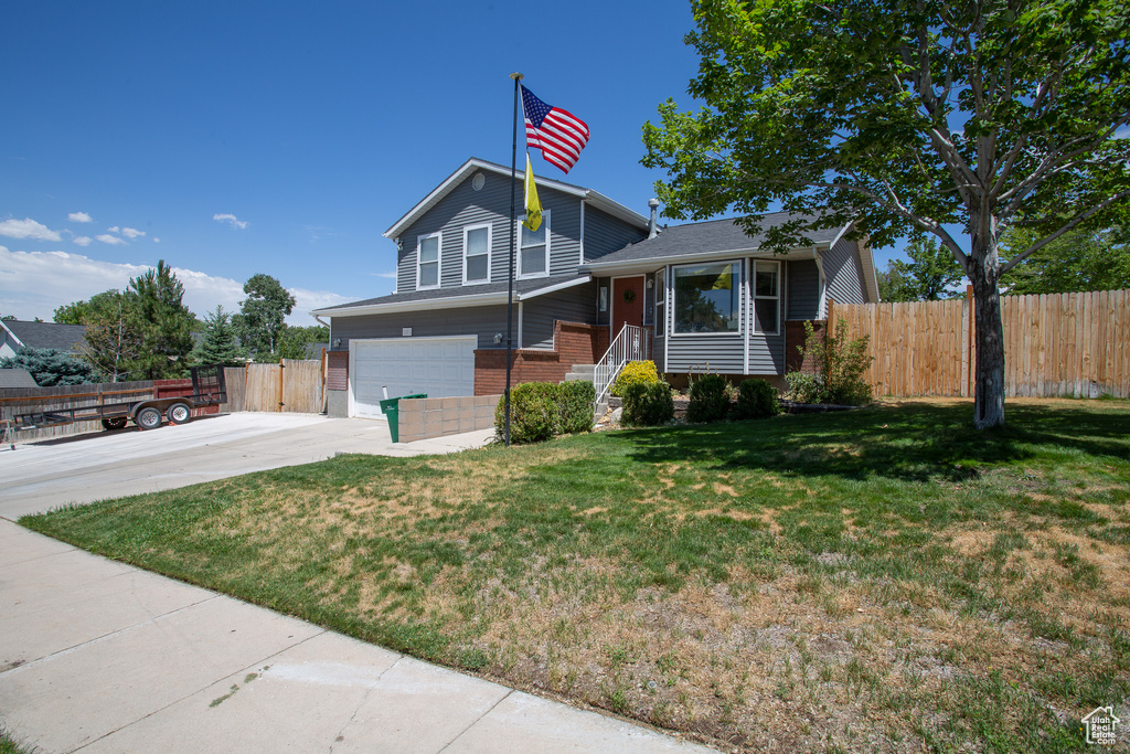 Tri-level home with concrete driveway, an attached garage, brick siding, and a chimney
