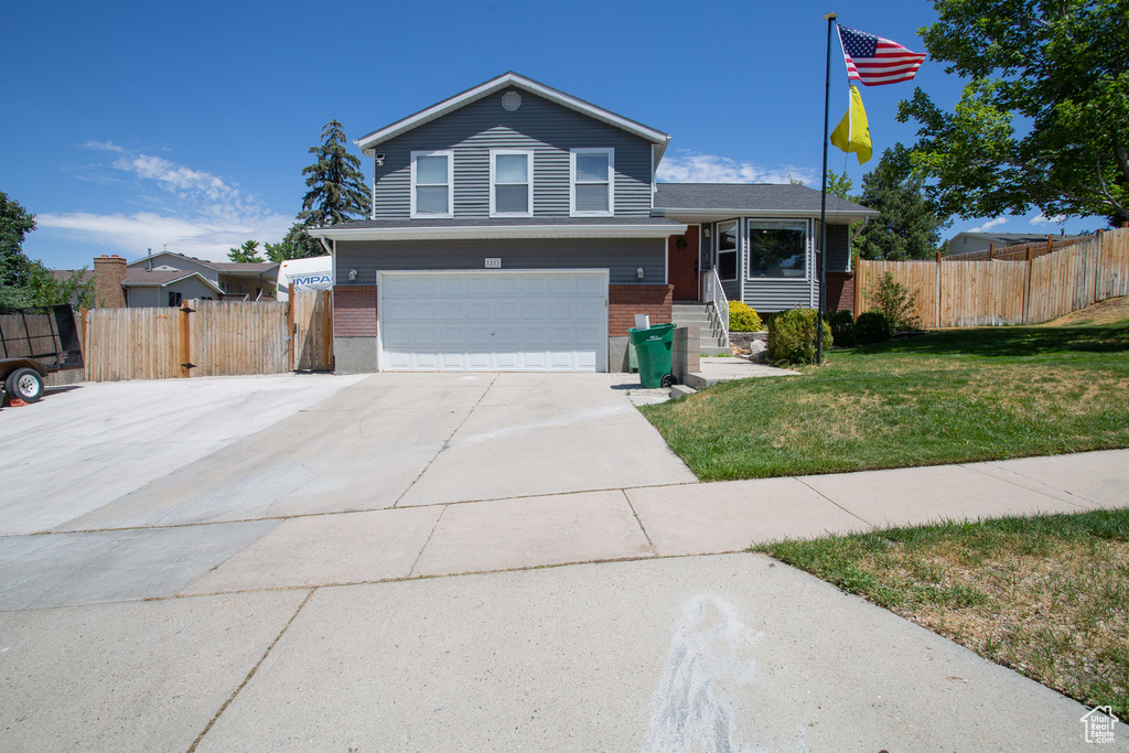 Split level home featuring brick siding, an attached garage, and driveway