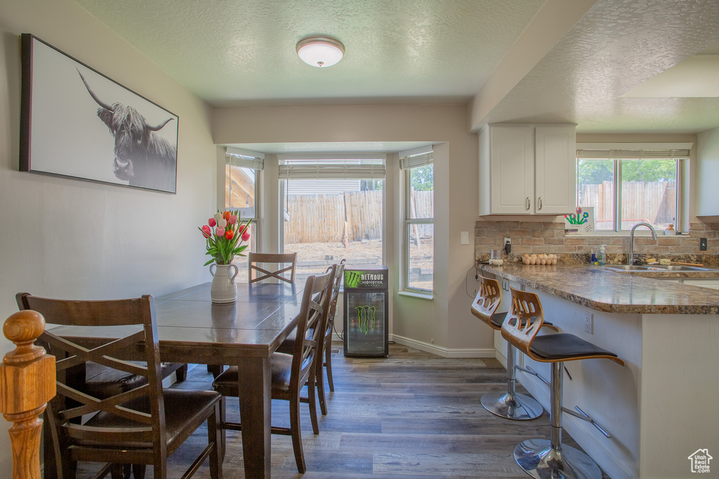Dining area featuring wood finished floors, plenty of natural light, and a textured ceiling