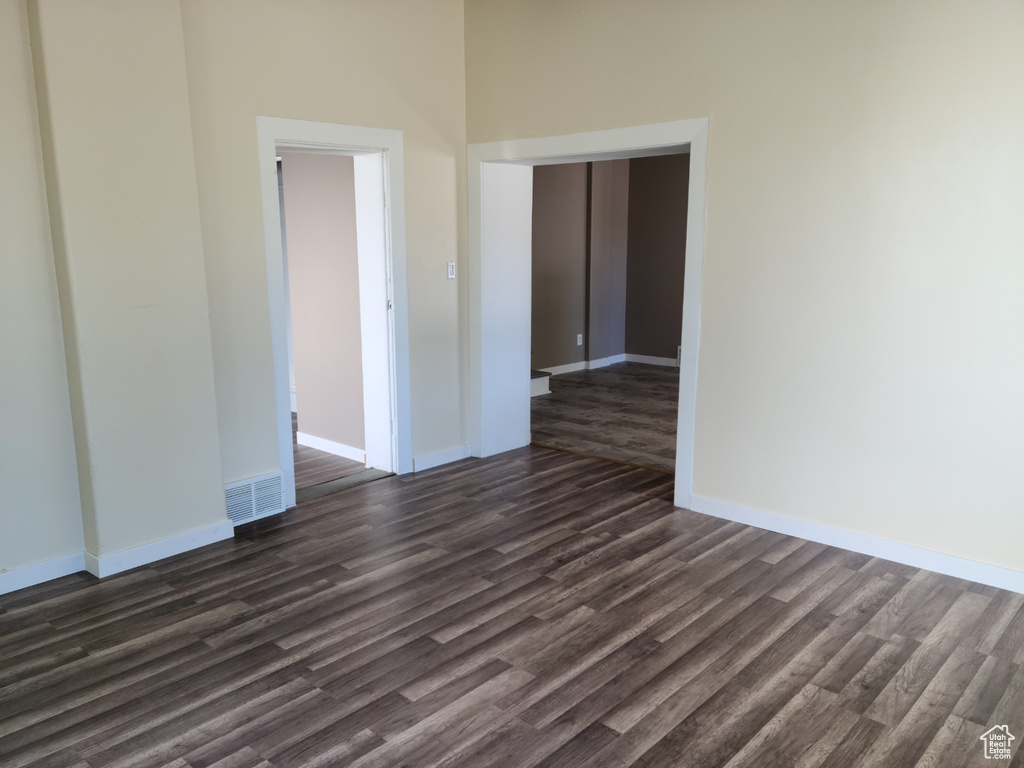 Spare room featuring dark wood-type flooring and baseboards