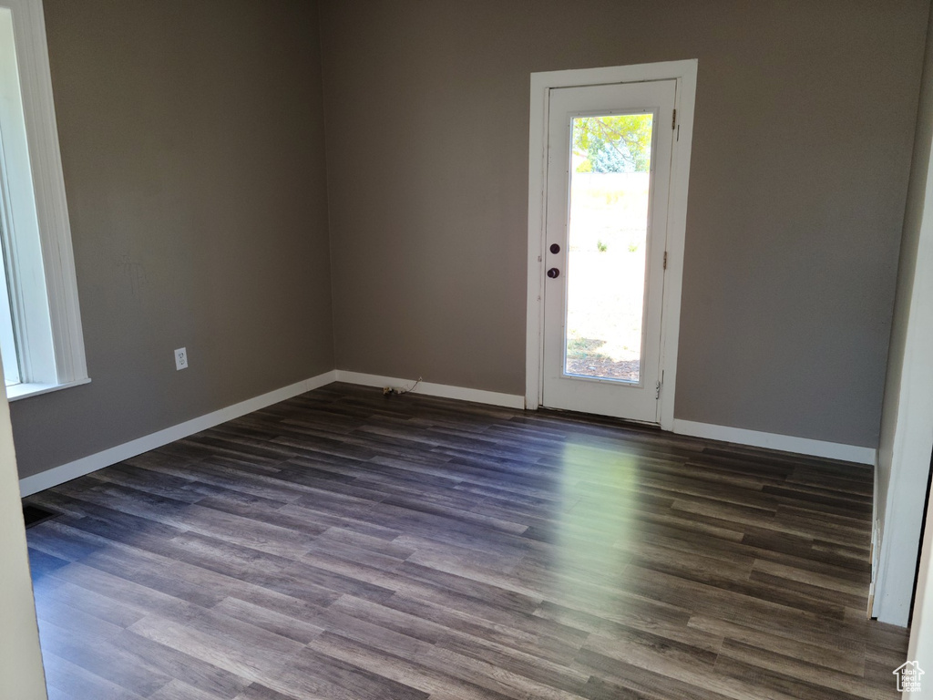 Spare room with dark wood-type flooring and baseboards