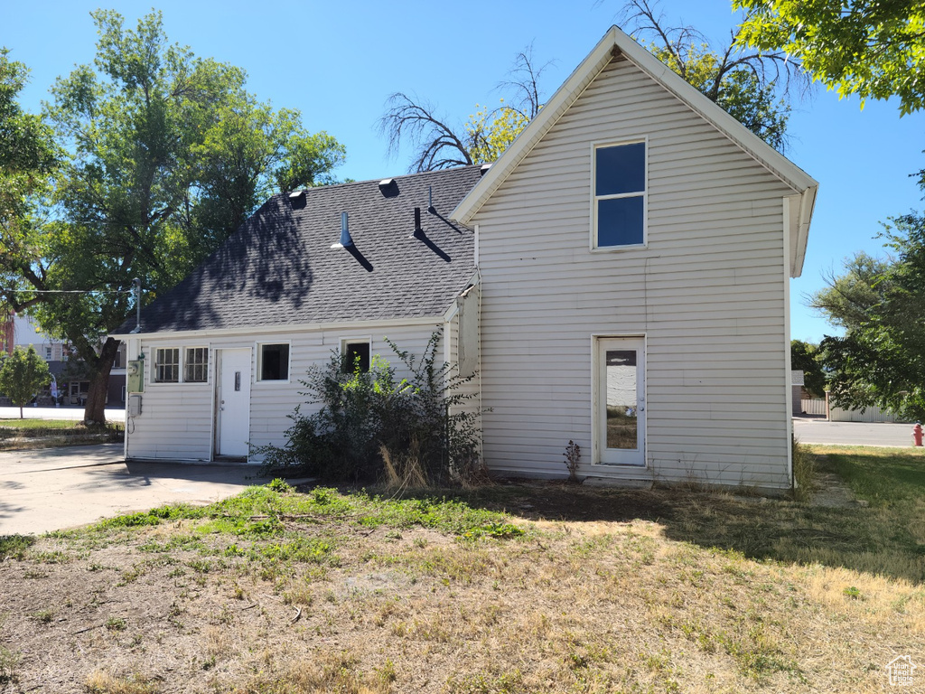 Back of house with roof with shingles and a yard