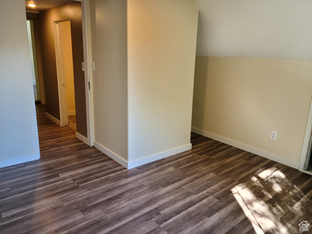 Spare room featuring dark wood-style flooring and baseboards