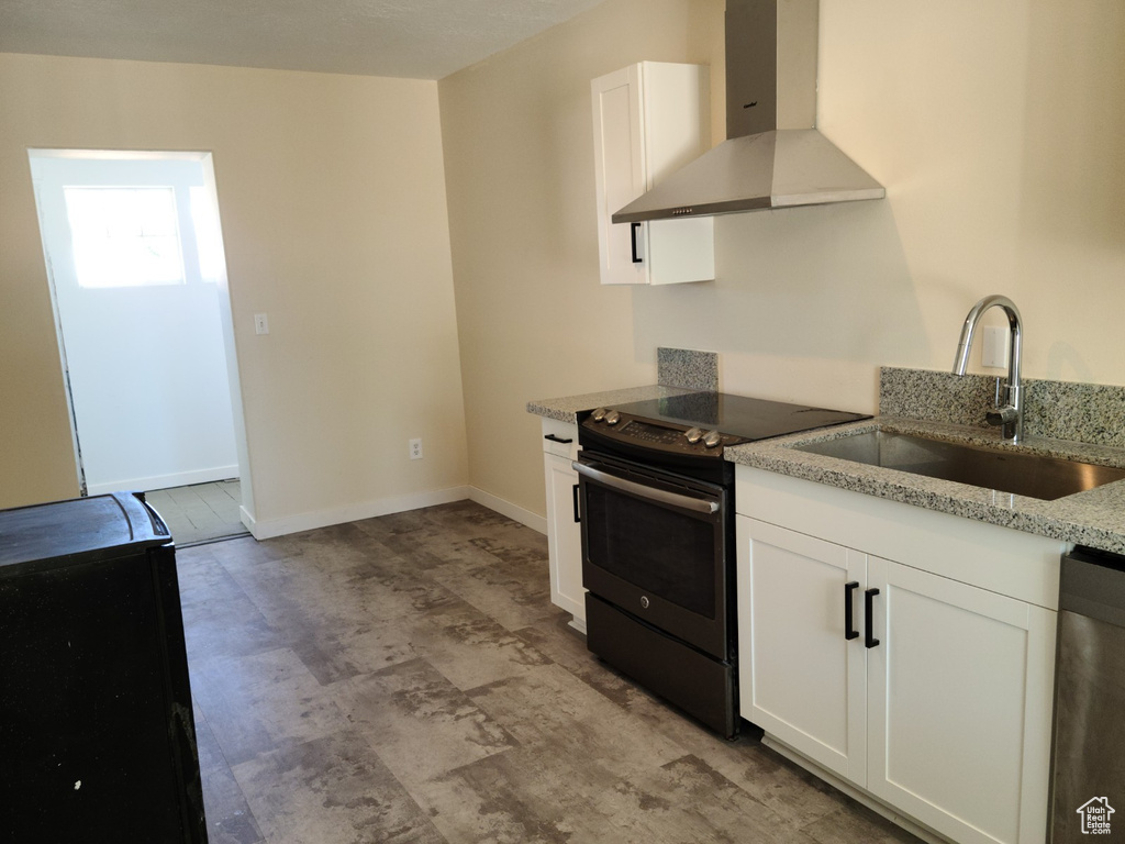 Kitchen featuring wall chimney exhaust hood, electric range, a sink, dishwasher, and white cabinets