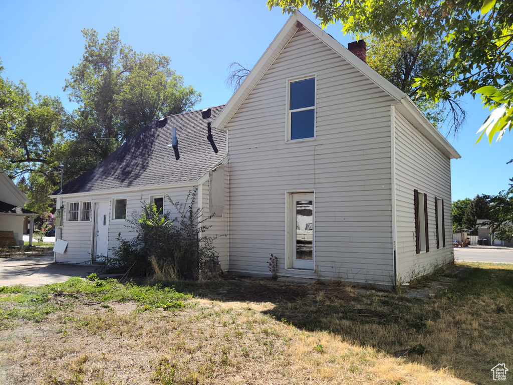 Back of house featuring a chimney and a shingled roof